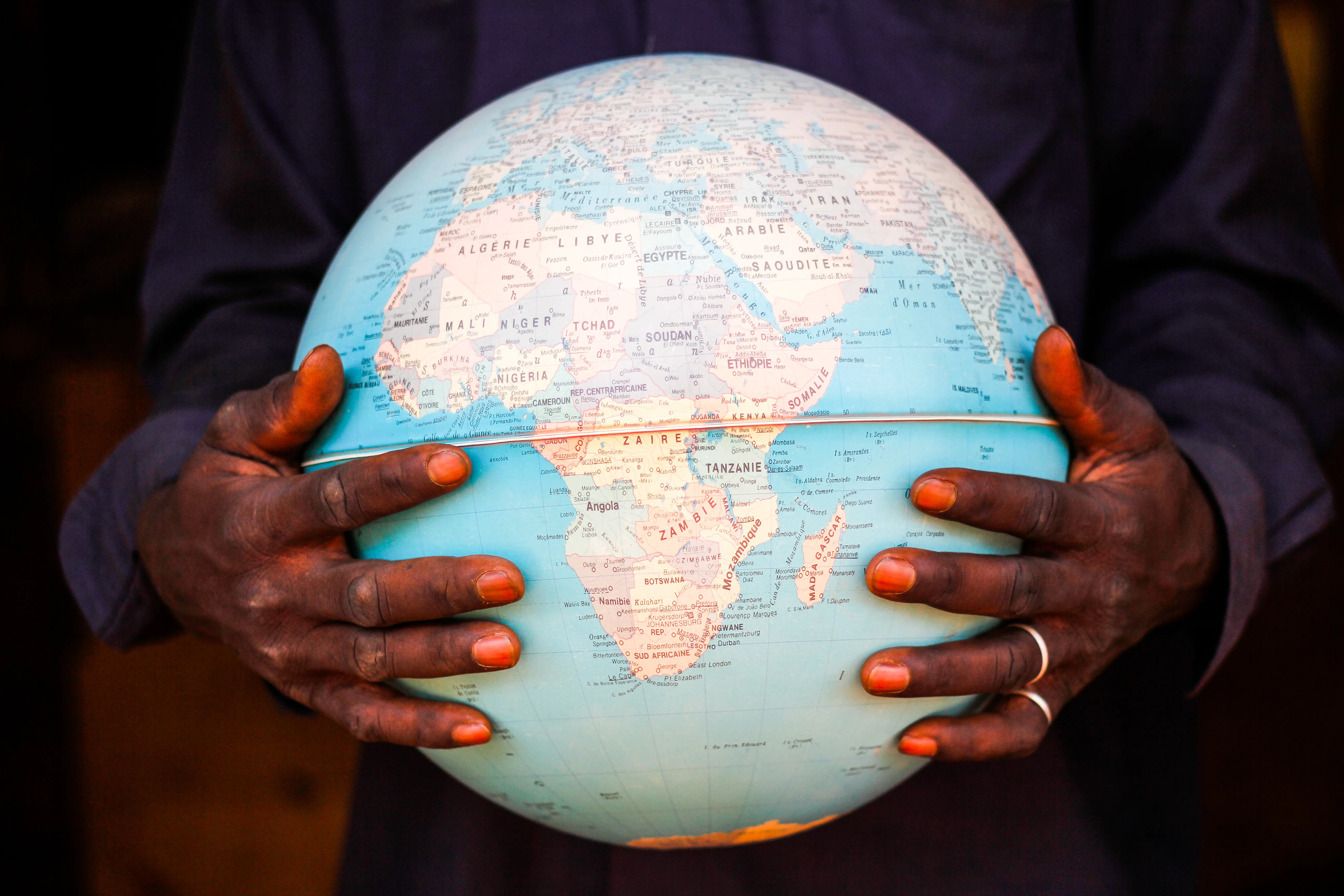 Hands holding a globe of the world depicting the African continent 