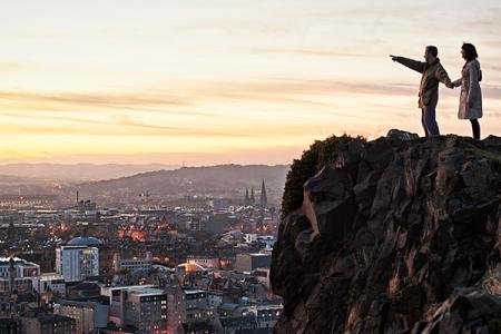 Students stand atop Arthurs seat with the City in the background