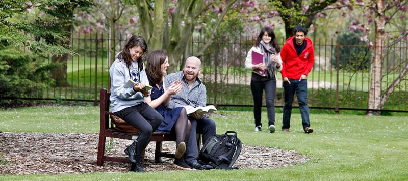 students sitting on a bench in a park 