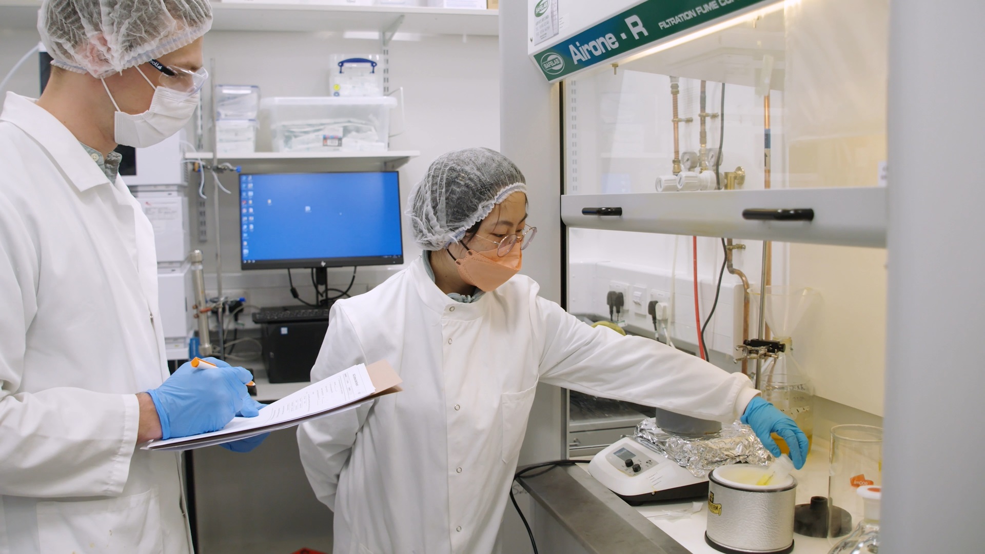 Two scientists in a laboratory wearing face masks